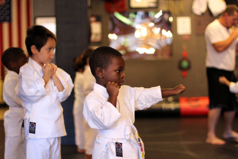 young child in martial arts uniform punching forward