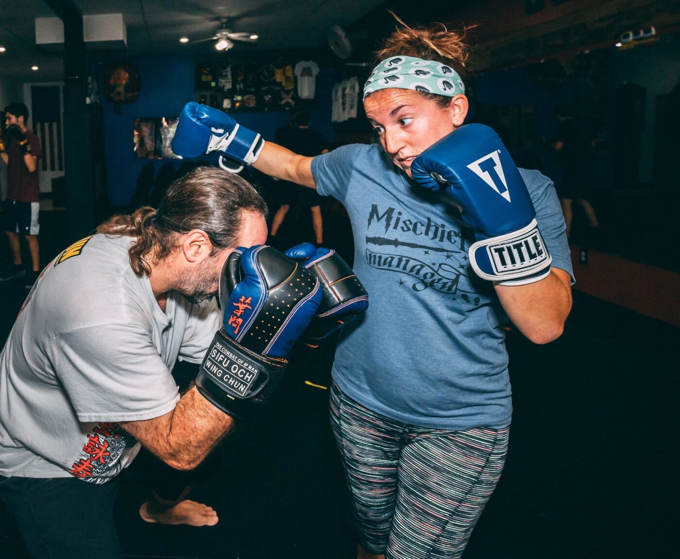 woman in boxing gloves throwing a punch at sparring partner, kickboxing lakeland, lakeland kickboxing, kickboxing woman, woman kickboxing, woman boxing, boxing lakeland, lakeland boxing,