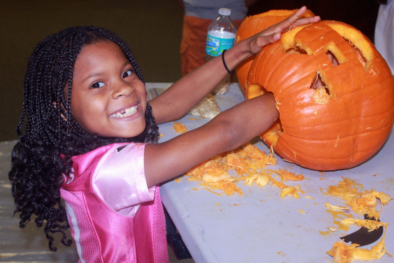 girl carving pumpkin smiling at camera