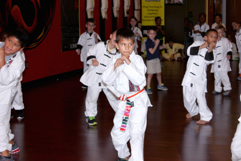 kid standing in group practicing martial arts technique
