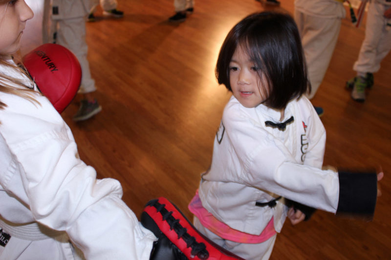 young child in martial arts uniform throwing punch