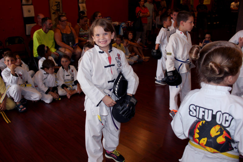 kids in wing chun martial arts uniforms and one smiling at camera