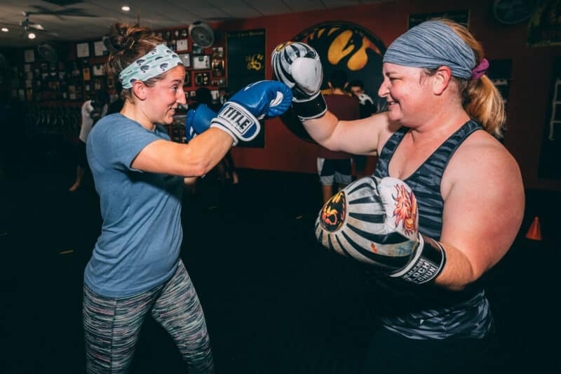 two women smiling wearing boxing gloves in kickboxing classes