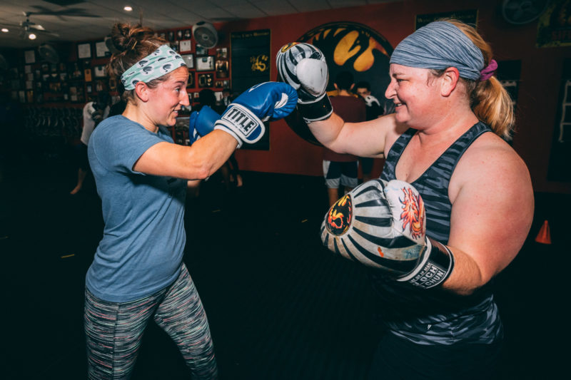 woman smiling while doing kickboxing training in martial arts studio